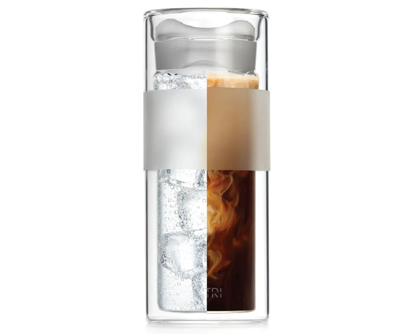 A split image of the VITRI All-glass Tumbler showcasing hot and cold drinks. The left half contains sparkling water with ice cubes and a lemon slice, while the right half contains hot coffee with milk swirling into it. The double-wall glass keeps each drink visually distinct, highlighting the tumbler's versatility for both hot and cold beverages. The all-glass lid and minimalist design emphasize a pure drinking experience.
